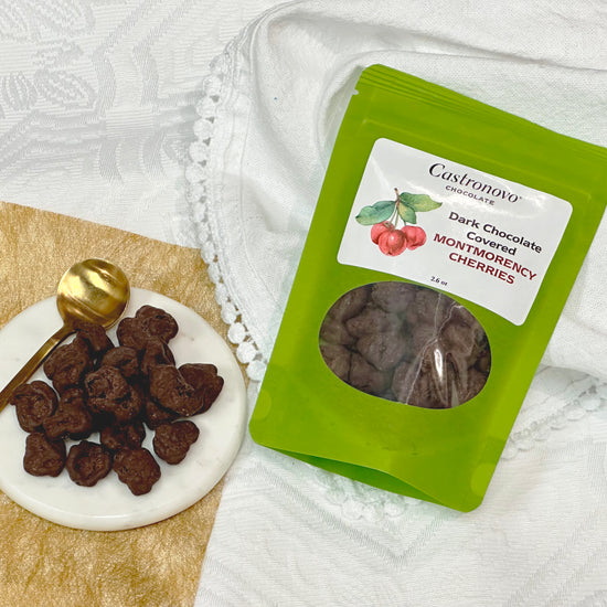 Castronovo dark chocolate-covered Montmorency tart cherries in green packaging, with product displayed on plate to side