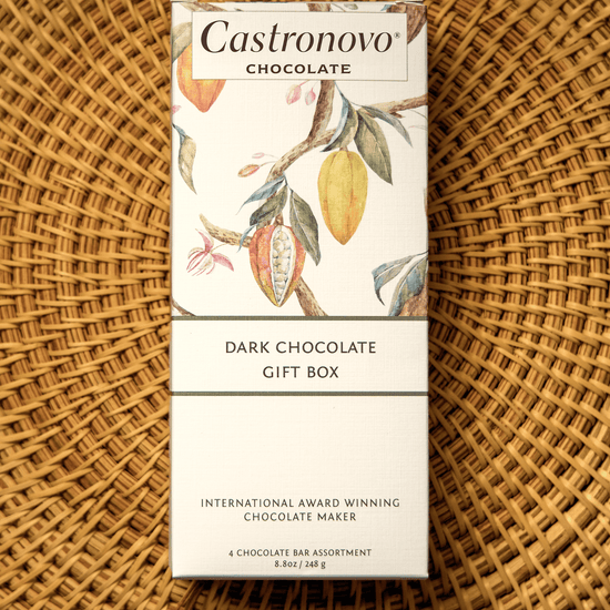 A packaged gift box of Castronovo dark chocolate bars with a floral design on the packaging, placed on a woven basket.