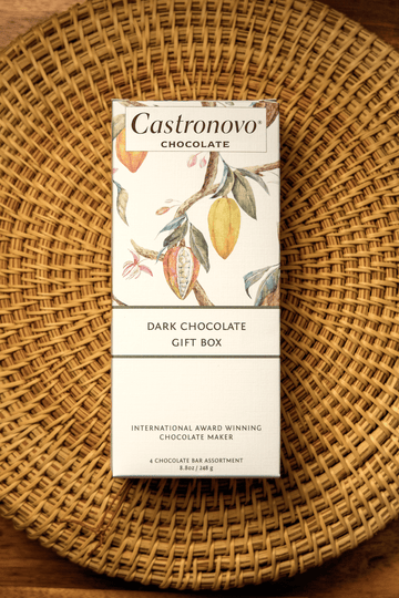 A packaged gift box of Castronovo dark chocolate bars with a floral design on the packaging, placed on a woven basket.
